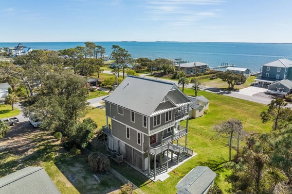 Oceanfront resort with swimming pool, multi-story building, and sandy beach with waves beyond